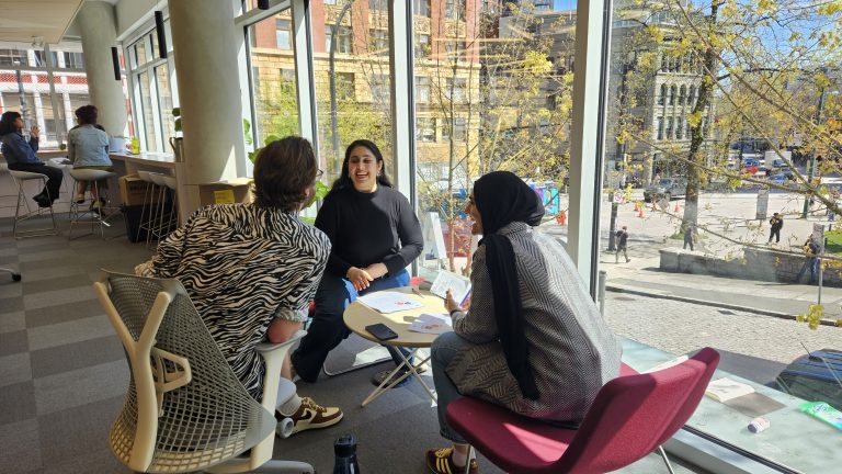 Photo of three people sitting together and smiling while talking