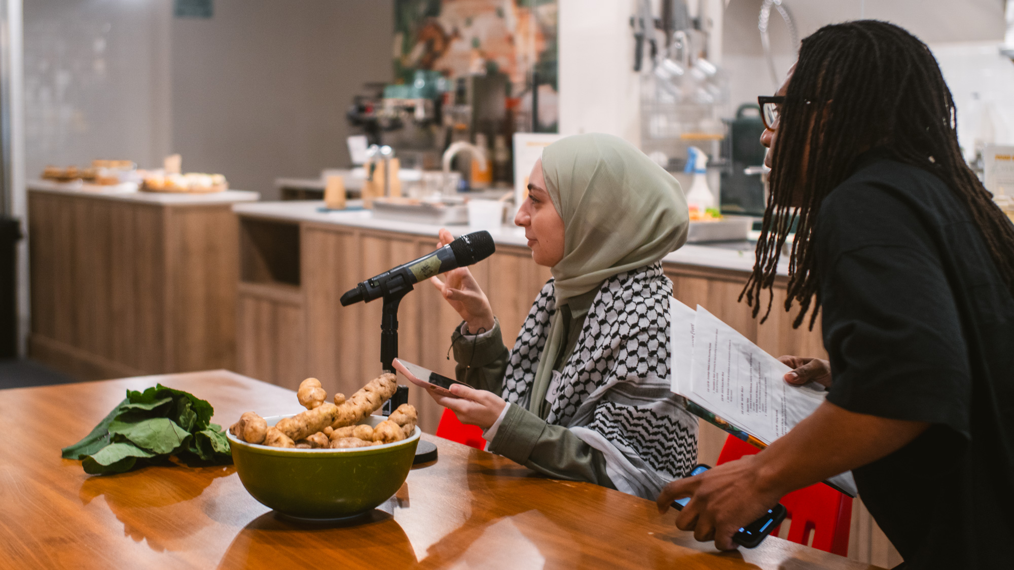 Person wearing hijab and a keffiyeh speaks on mic